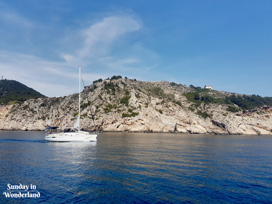 Sail Trip in Montenegro - a sailing yacht with a cliff shore in a background - Sunday In Wonderland Travel Blog