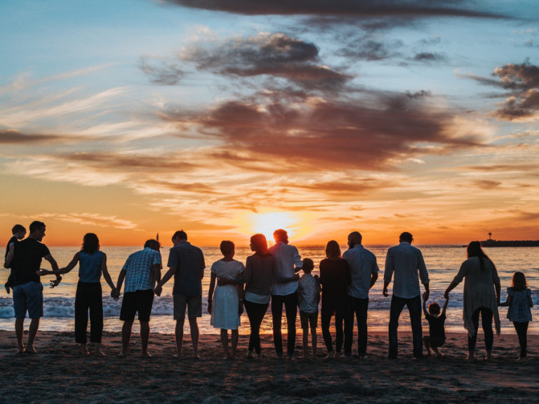 Duża rodzina stojąca na plaży w zachodzącym słońcu