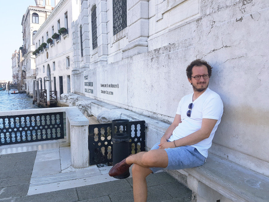 A man sitting in front of Peggy Guggenheim Collection in Venice