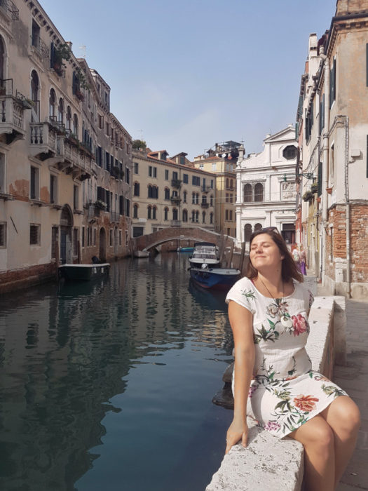 A girl posing sitting next to the canal in Venice