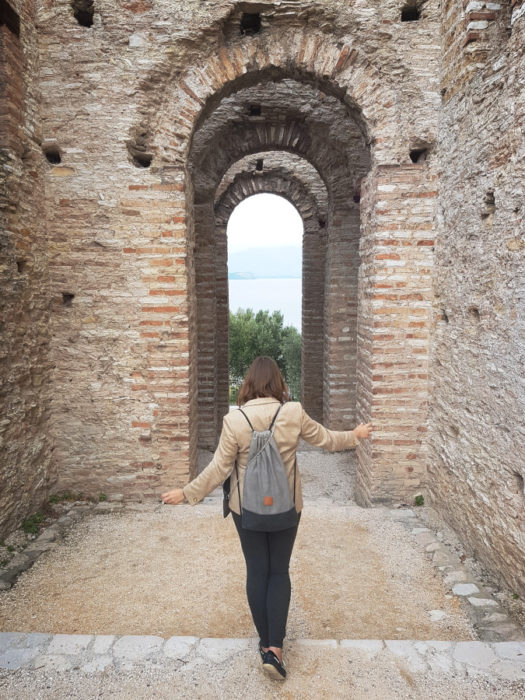 A girl walking among the ruins of ancient Roman villa in Grotte di Catullo in Sirmione, Italy, Lake Garda