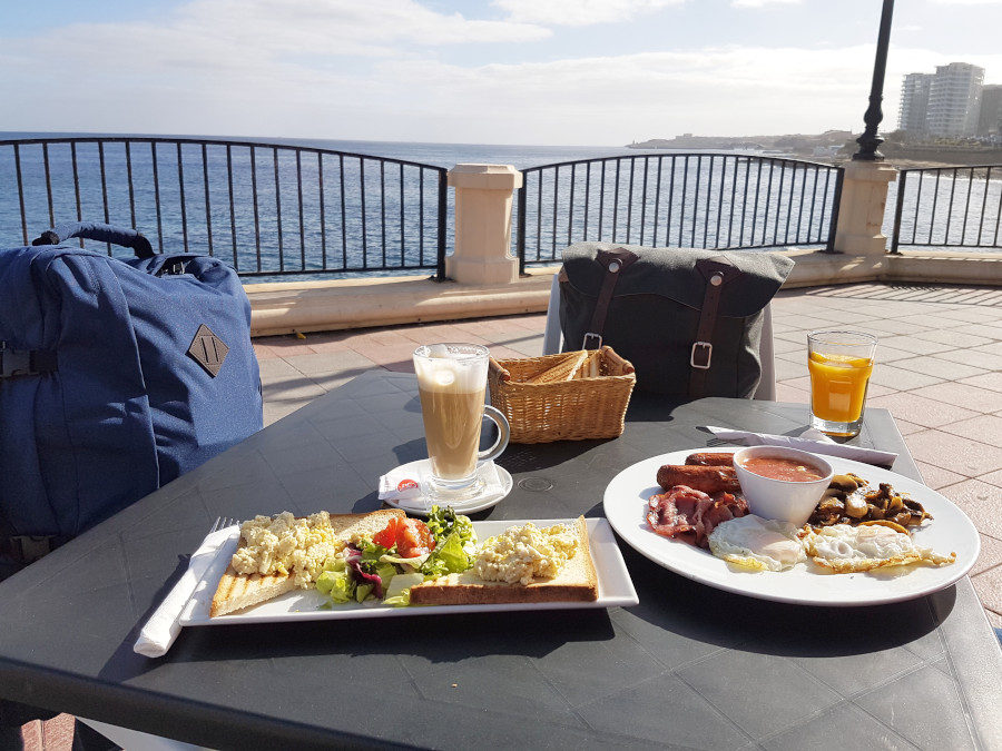 Outside breakfast table with two travel backpacks on chairs in Malta in winter