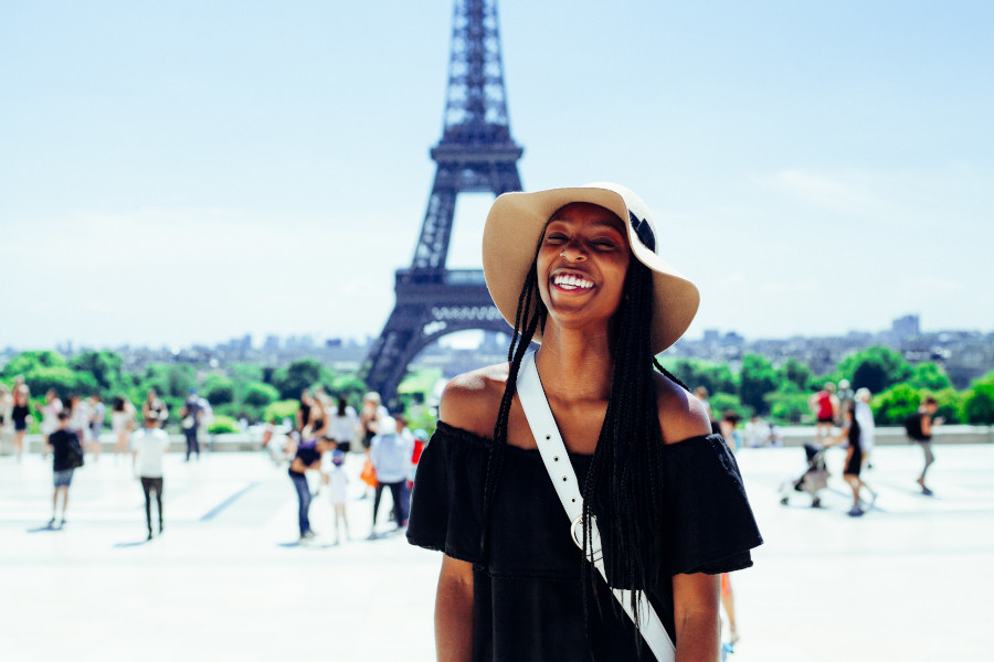 A girl in a summer hat standing in front of the Eiffel Tower