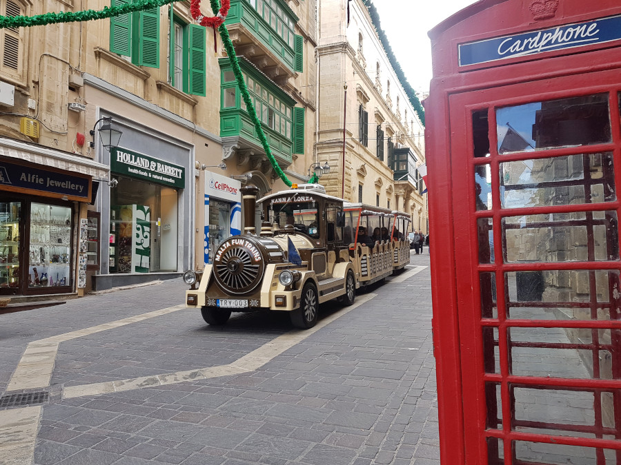 The tourists train in Valletta with a red Eglish phone cabin