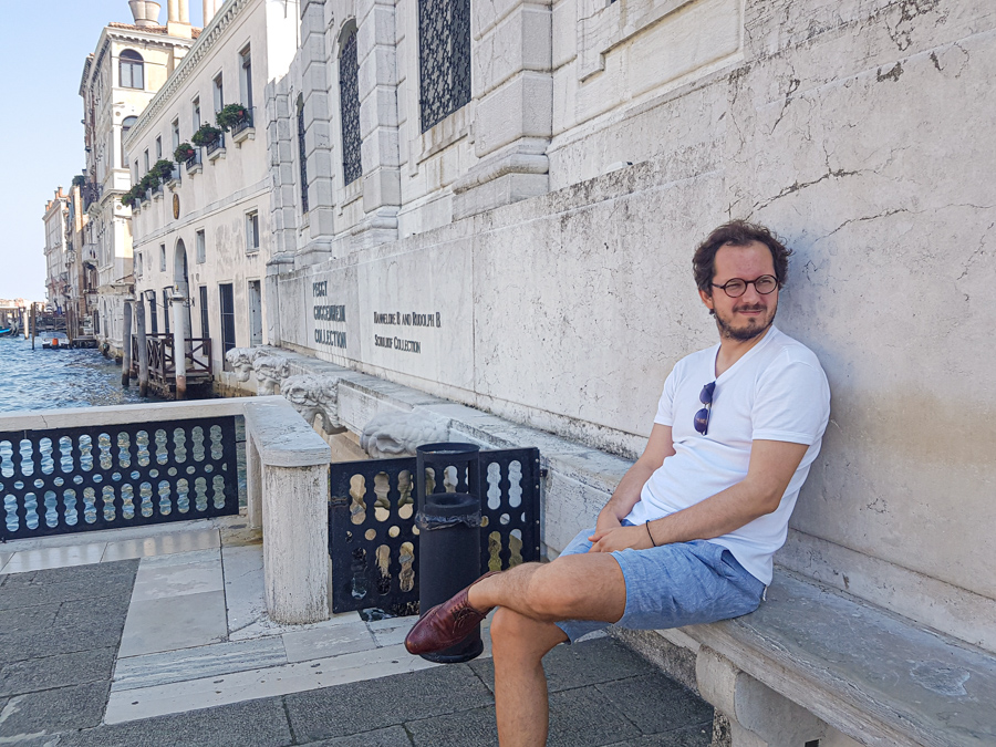 A man sitting on the stone bench in front of the Peggy Guggenheim's museum in Venice, Italy
