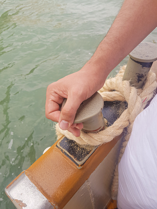 A man's hand holding the mooring puller on the Vaporetto